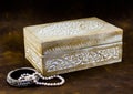 Antique carved pale wood box with peal jewellery on dark brown b