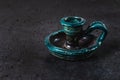 Antique ceramic candlestick of turquoise color on gray cement background, ancient object designed for candles representing