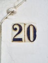 Antique ceramic tile number 20 on a whitewashed wall