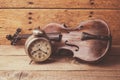 Antique clock and old violin over vintage wooden table Royalty Free Stock Photo