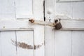 Antique closed door painted with white and locked with rusty lat