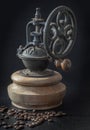 Antique coffee bean original grinder metal shake wheel with hand crank and coffee beans on dark background Royalty Free Stock Photo