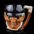 Antique coffee cup in the shape of a man`s head on a black background.