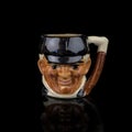 Antique coffee cup in the shape of a man`s head on a black background.