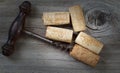 Antique corkscrew with used corks on aged wood