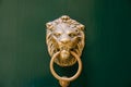 Antique door handle on a green wooden door in the shape of a lion`s face with a knock ring in the mouth. Royalty Free Stock Photo