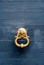 Antique door handle-ring in gilding on a blue wooden door.