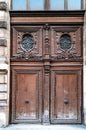 Antique double door gate with of aged ornate carving fretwork wooden panels and door windows of building in Paris France. Royalty Free Stock Photo
