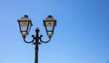 Antique double metal lamppost on blue sky background. Cyclades island, Greece. Under view. Space