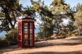 Antique english telephone booth as a famous image set up in a forest park by the sea. general plan.