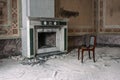 An antique fireplace and a chair next to it in an old abandoned manor house. Royalty Free Stock Photo