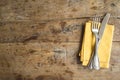 Table setting with antique fork and knife, yellow linen napkin on old wooden background. Space for text, flat lay