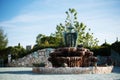 Antique fountain in the garden of the old castle. Stone walkway. Alley in beautiful garden with flowers and trees around. Summer Royalty Free Stock Photo