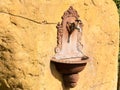 Antique French ornate wall fountain lavabo or planter with scrolling details and accents mounted in a stone block outside. A tap i