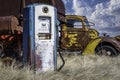 Antique gas pump and vintage combine and truck in the background