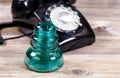 Antique glass insulator and rotary dial phone on rustic wooden b