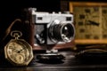 Antique gold pocket watch with a retro film camera and table clock on blurred background. Golden round pocket watch with Royalty Free Stock Photo