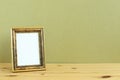 Antique golden picture frame on wooden table with khaki background Royalty Free Stock Photo