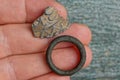 An antique gray piece of metal with a pattern and a black rusty iron ring