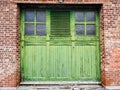 Antique Watervliet Shaker green bifold garage door in brick wall Royalty Free Stock Photo