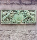 Antique green coat of arms on a red stone wall