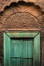 Antique green door with carved ornaments in an arched doorway on the wall of an ancient residential building in India. Vertical or Royalty Free Stock Photo