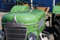 Antique green farm tractor parked on a side road alongside other vintage tractors