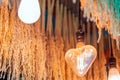 Antique heart shaped light bulbs hanging with green and gold color dried ear of rice to decorate in the coffee shop. Selective