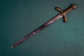 Antique knightly sword on a green velvet background.