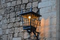 Antique lamppost lantern attached to medieval wall of castle. Light on