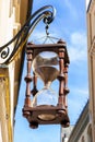 Antique large hourglass hanging in old town. Multicolored vibrant outdoors