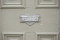 Antique mail slot on wooden door.