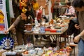 Antique market trader showing some crockery and old statues for customers