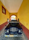 An antique navy blue convertible off-road car standing at the gate