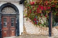 Antique oak door in an old stone house decorated with bright petunia flowers on a cloudy summer day Royalty Free Stock Photo