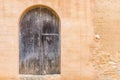 Antique old gray wood front door with stone arch and rustic stone wall Royalty Free Stock Photo