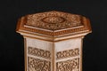 Antique oriental wooden table with the artistic carving on a black background, Uzbekistan, close-up