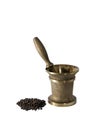 Ancient bronze mortar and a handful of black pepper peas on a white background