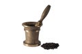 Ancient bronze mortar and a handful of black pepper peas on a white background