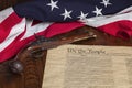 Antique pistol with thirteen star flag and the constitution of the United States on dark wood background