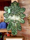 An antique plate in the shape of a green man\'s face.