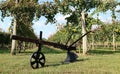 Antique plow with single wheel, in front of a vineyard in the countryside.