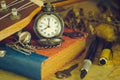 An antique pocket watch leaned against a ukulele and old book with vintage map and brass pen placed on wooden table. Royalty Free Stock Photo