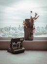 Aantique polaroid camera, Sunglasses and Dried flowers in mini brown leather bag. Background it city and river view