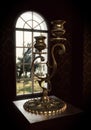 Old bronze candelabra stand in front of the window
