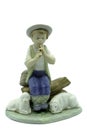 Antique porcelain figure of a boy shepherd playing the whistle or pipes sitting on a log with two sheep or lambs at his feet Royalty Free Stock Photo