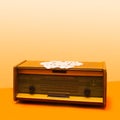 An antique radio with unique vintage crochet cloth table on it. Old school arrangement against beige and light orange background Royalty Free Stock Photo