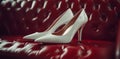 An antique red car seat rests on white high heels Royalty Free Stock Photo