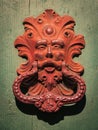 Antique red door knocker of an old door in Italy. Royalty Free Stock Photo