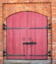 Antique red wood door with barn lock in orange brick wall Royalty Free Stock Photo